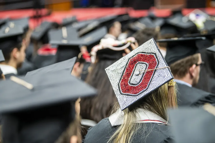 A student sitting for graduation with a sparkly Block O on their cap. 